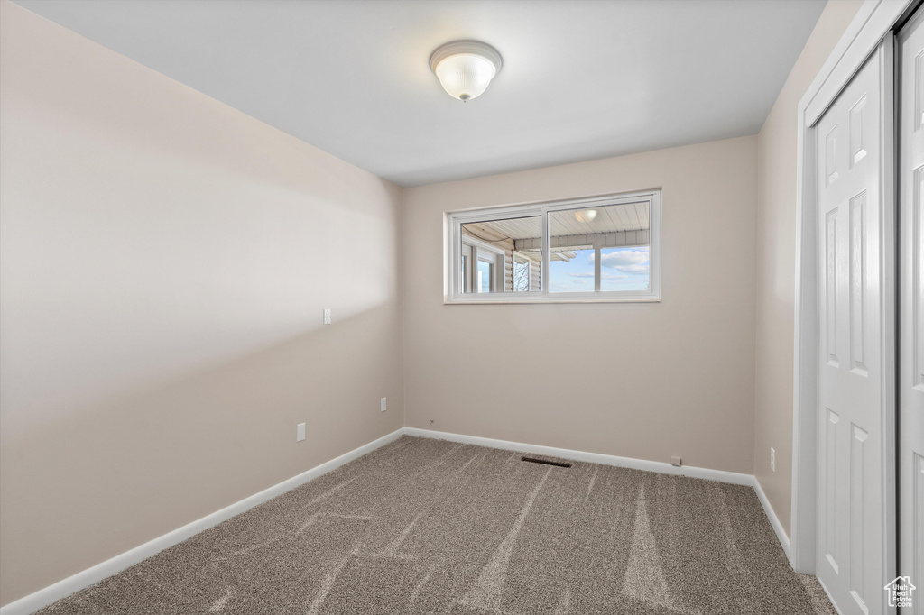 Unfurnished bedroom featuring a closet, carpet flooring, visible vents, and baseboards