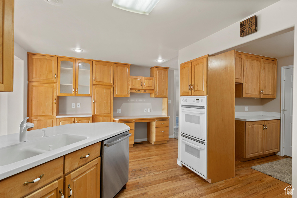 Kitchen with double oven, stainless steel dishwasher, light wood-type flooring, and a sink