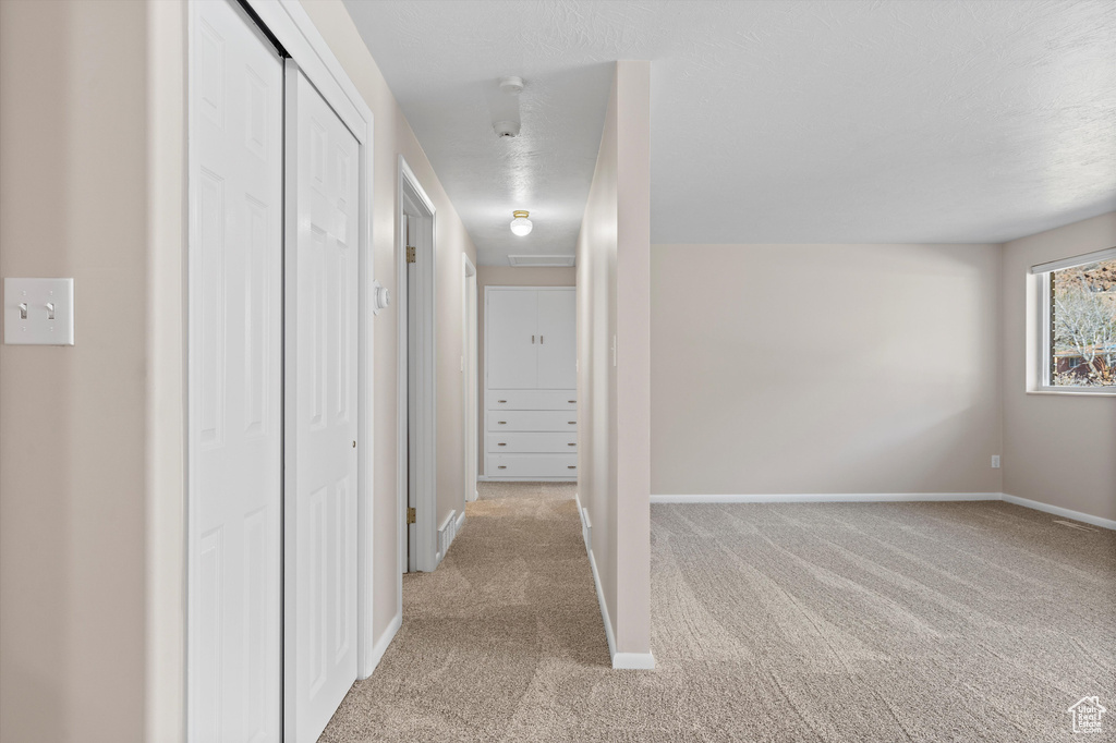 Hall featuring baseboards and light colored carpet