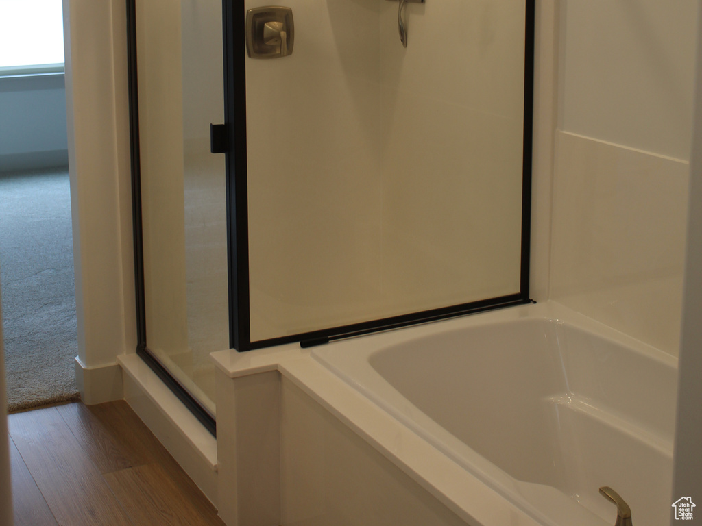 Full bathroom with wood finished floors, a stall shower, and a garden tub