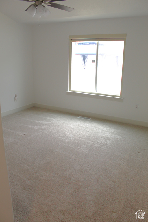 Spare room with light carpet, a ceiling fan, and baseboards