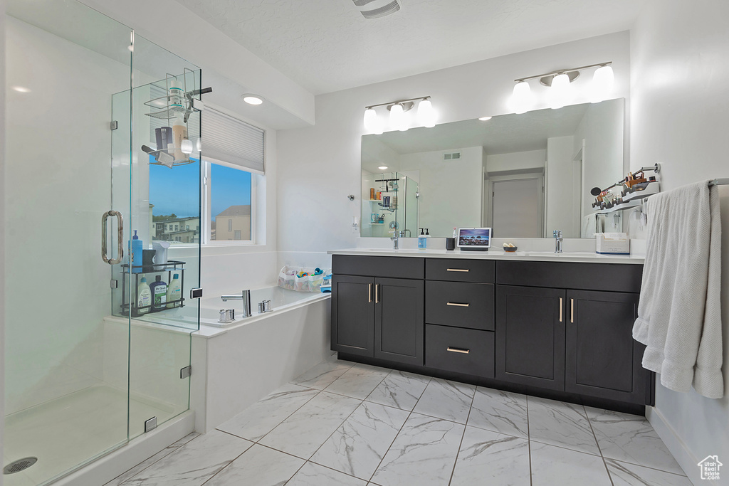 Full bathroom with marble finish floor, double vanity, a stall shower, a sink, and a bath