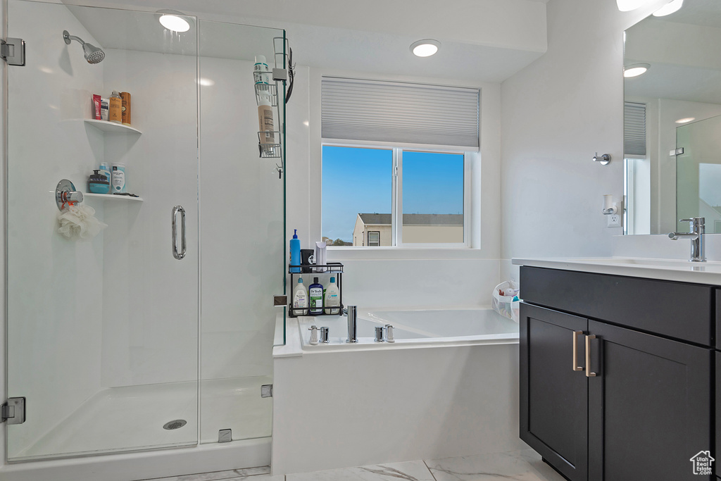 Full bath featuring marble finish floor, vanity, a garden tub, and a stall shower