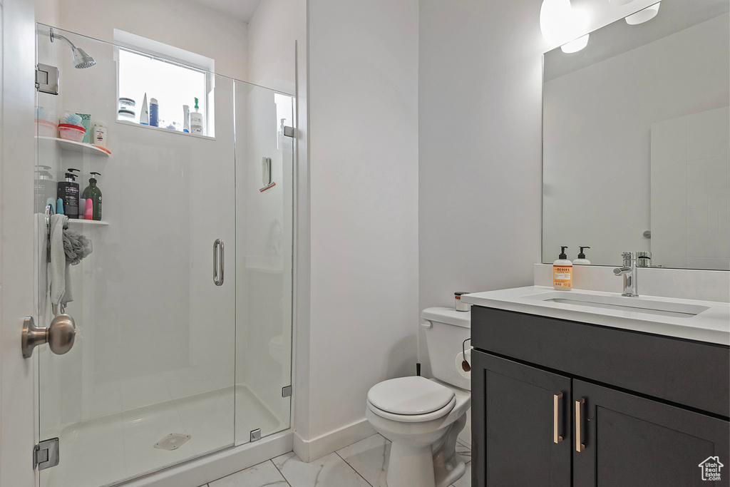 Bathroom featuring toilet, vanity, baseboards, marble finish floor, and a stall shower