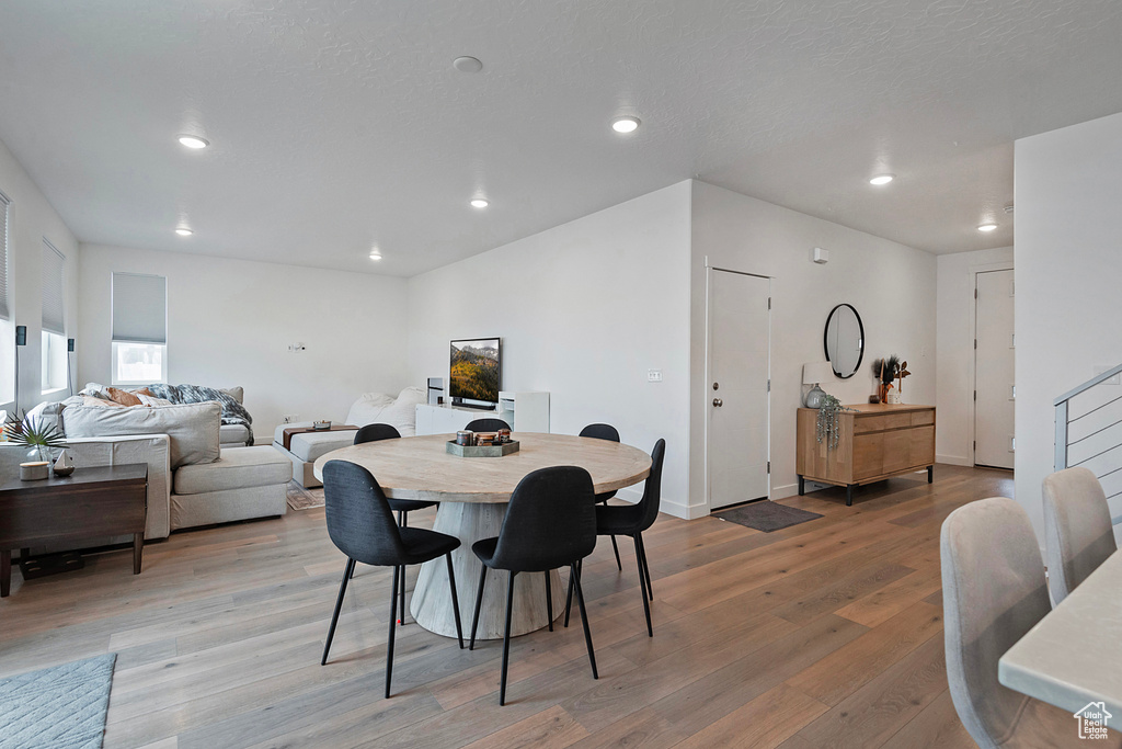 Dining space featuring recessed lighting, stairway, light wood-style flooring, a textured ceiling, and baseboards