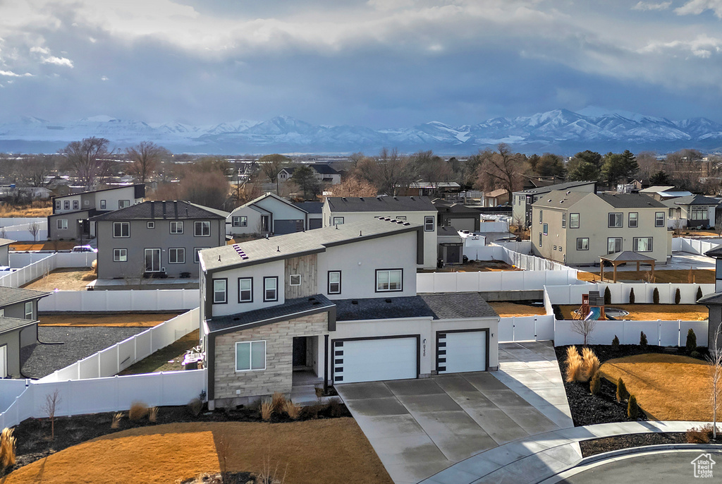 View of front facade featuring a mountain view, a fenced backyard, and a residential view