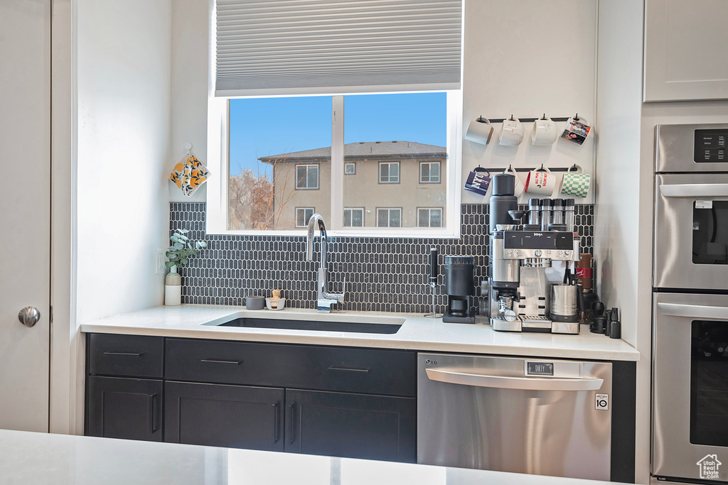 Kitchen featuring light countertops, appliances with stainless steel finishes, backsplash, and a sink