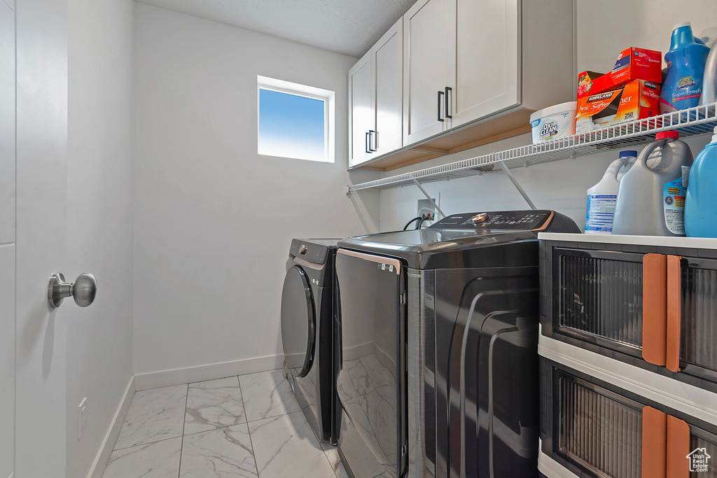 Laundry area featuring baseboards, marble finish floor, and washer and dryer