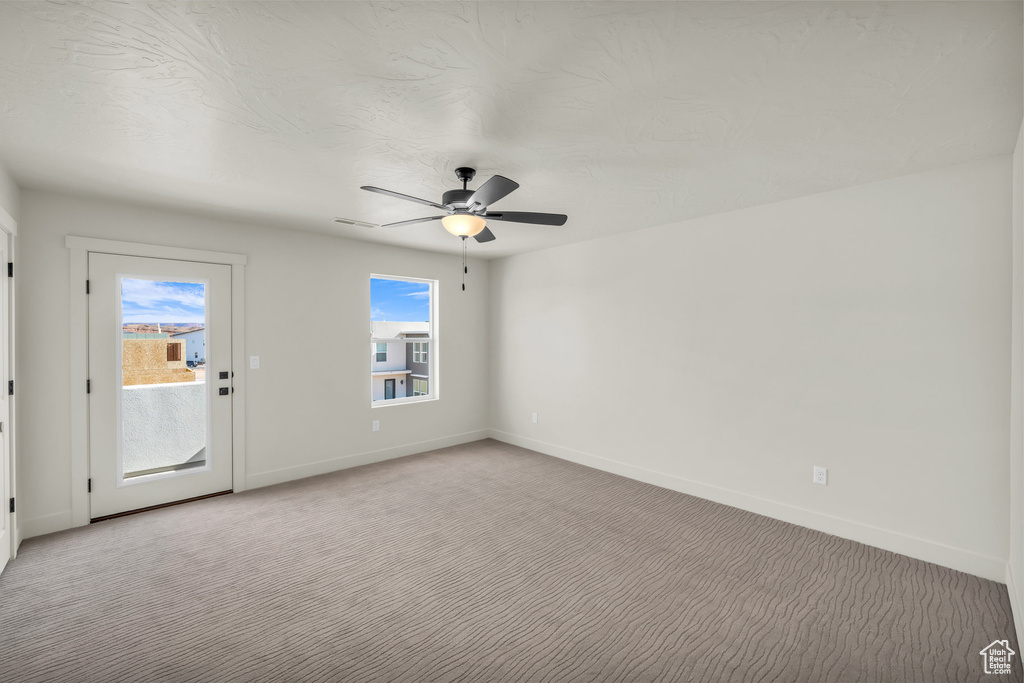 Spare room featuring ceiling fan, baseboards, and light colored carpet