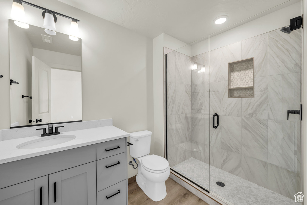 Full bathroom featuring toilet, wood finished floors, visible vents, vanity, and a stall shower