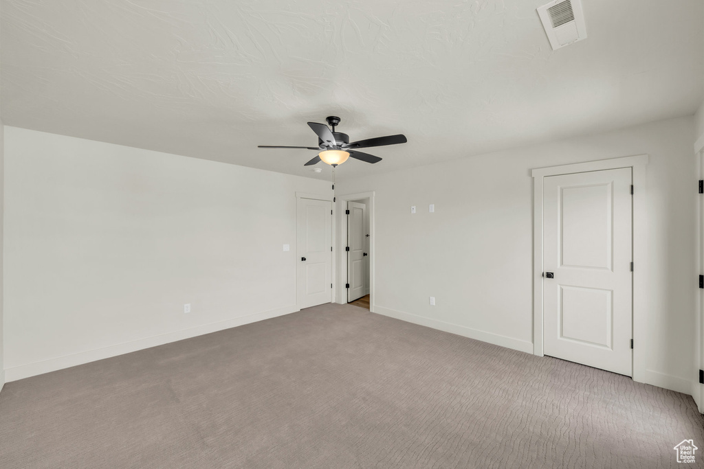 Spare room featuring baseboards, visible vents, a ceiling fan, and light colored carpet