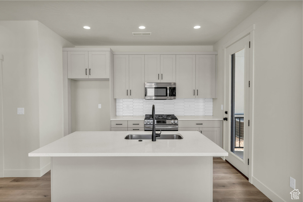 Kitchen featuring tasteful backsplash, visible vents, appliances with stainless steel finishes, light wood-style floors, and a sink