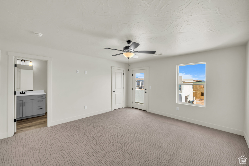Interior space with light colored carpet, ensuite bath, and baseboards