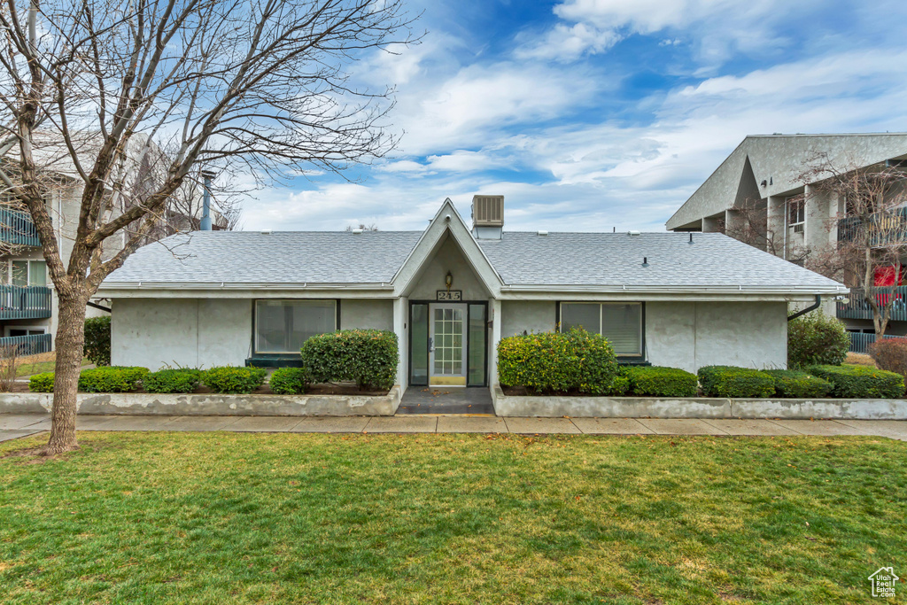 View of front of home featuring a front lawn, roof with shingles, and stucco siding