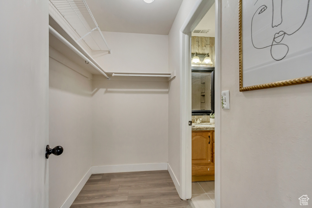 Spacious closet with a sink, visible vents, and wood finished floors