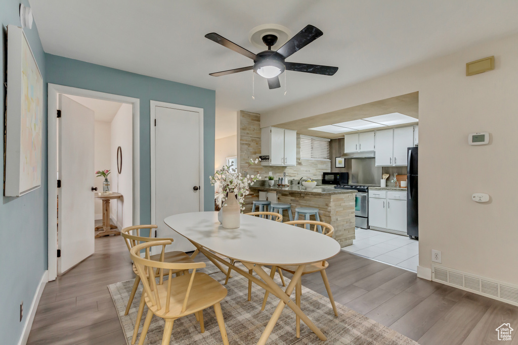 Dining room featuring baseboards, ceiling fan, and light wood finished floors