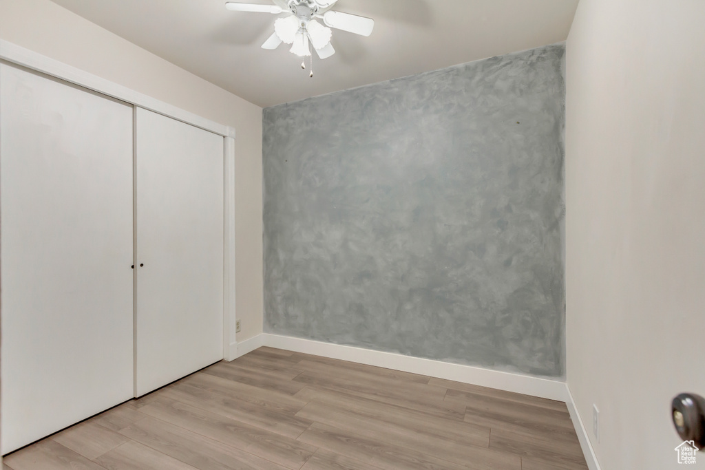 Unfurnished bedroom featuring baseboards, a closet, a ceiling fan, and light wood-style floors