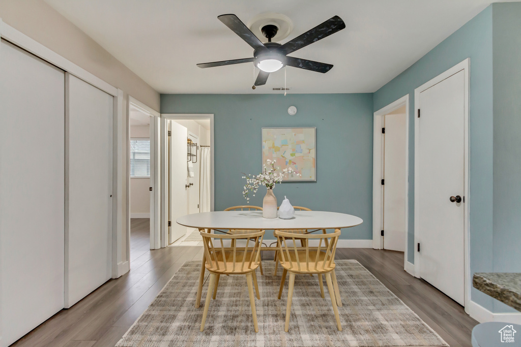 Dining space with wood finished floors, a ceiling fan, and baseboards