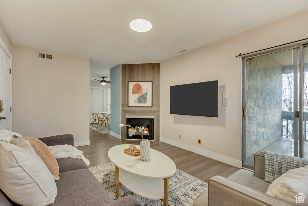 Living area with baseboards, a fireplace, visible vents, and wood finished floors