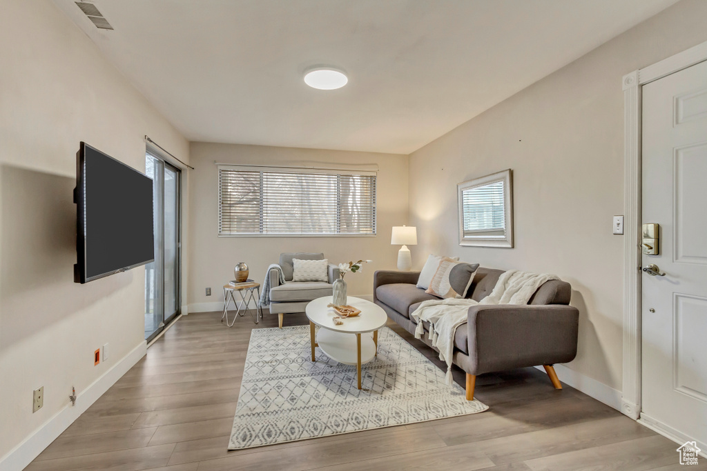 Living room with plenty of natural light, wood finished floors, visible vents, and baseboards