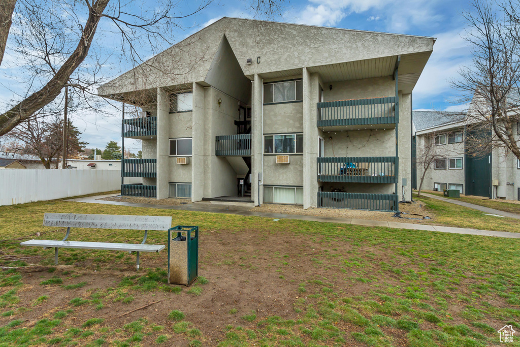 Back of property with a lawn, fence, and stucco siding