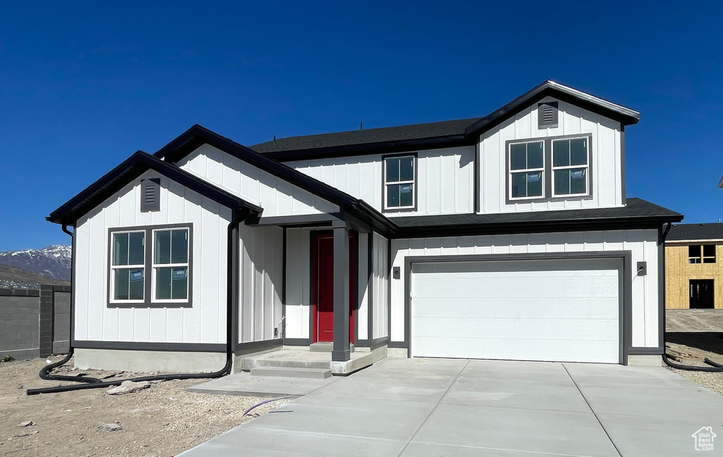 View of front of property with concrete driveway and an attached garage