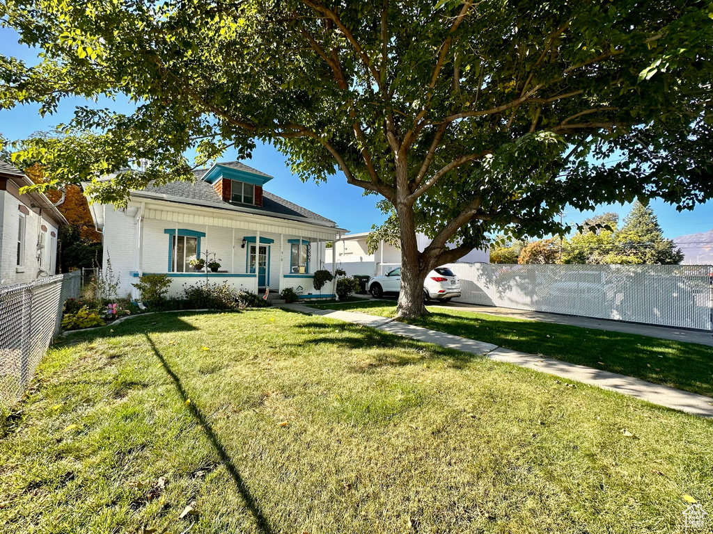 Exterior space with a porch, a front yard, and fence