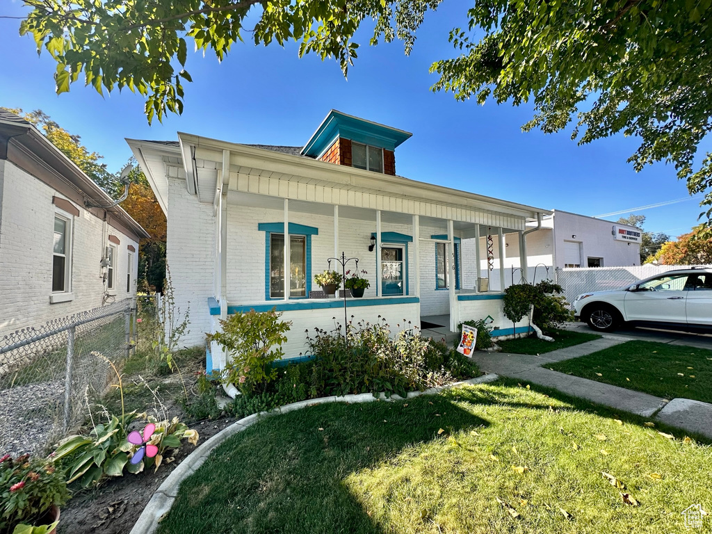 Bungalow-style house featuring a porch, a front yard, brick siding, and fence