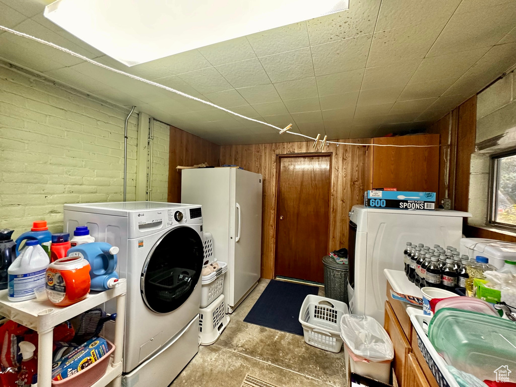 Washroom featuring laundry area, wood walls, and brick wall
