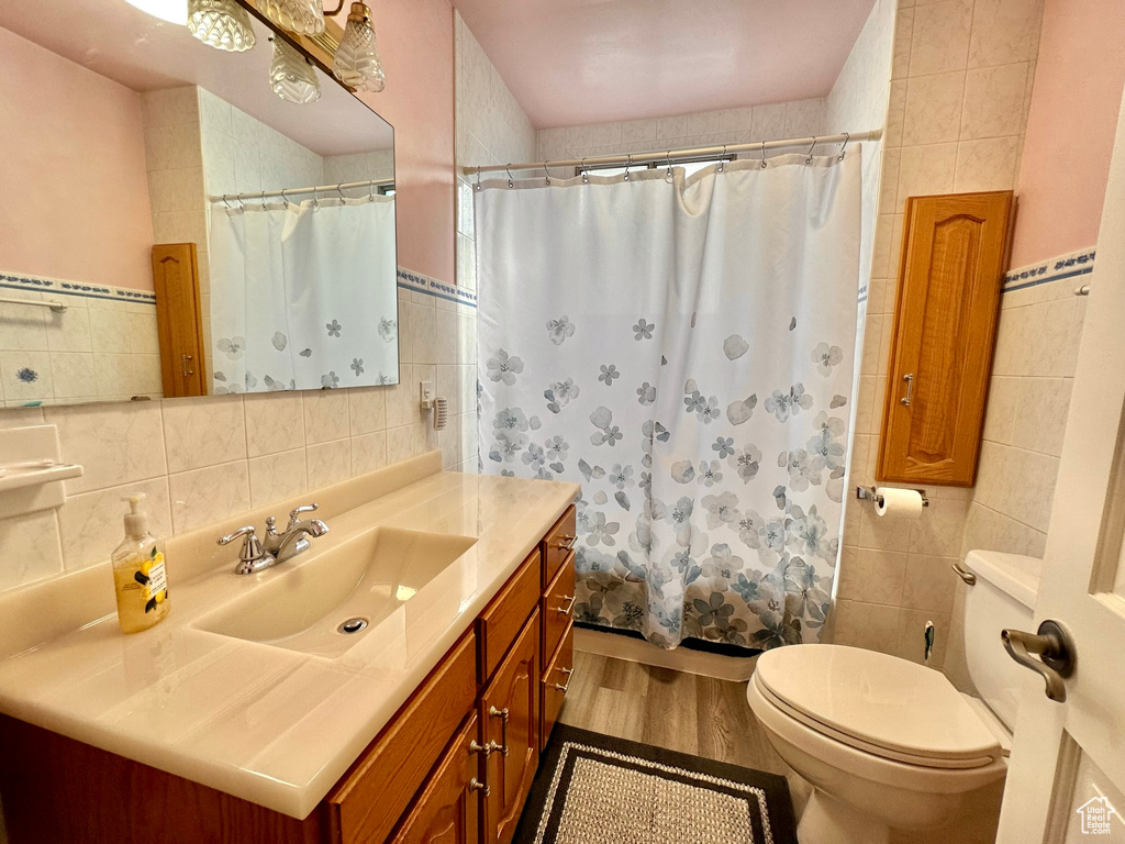 Bathroom with toilet, wood finished floors, tile walls, and vanity