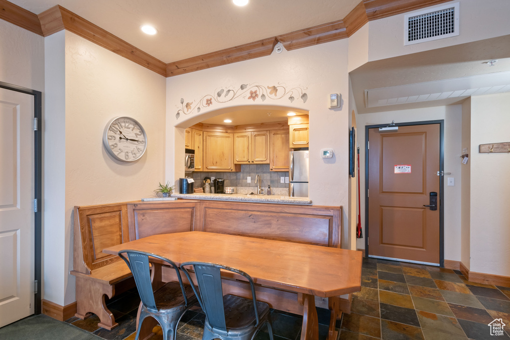 Kitchen featuring stainless steel appliances, visible vents, backsplash, stone finish floor, and crown molding