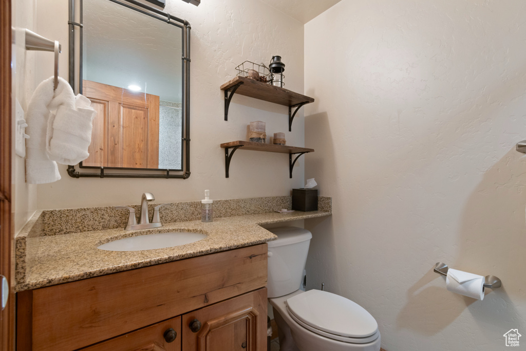 Bathroom featuring a textured wall, vanity, and toilet