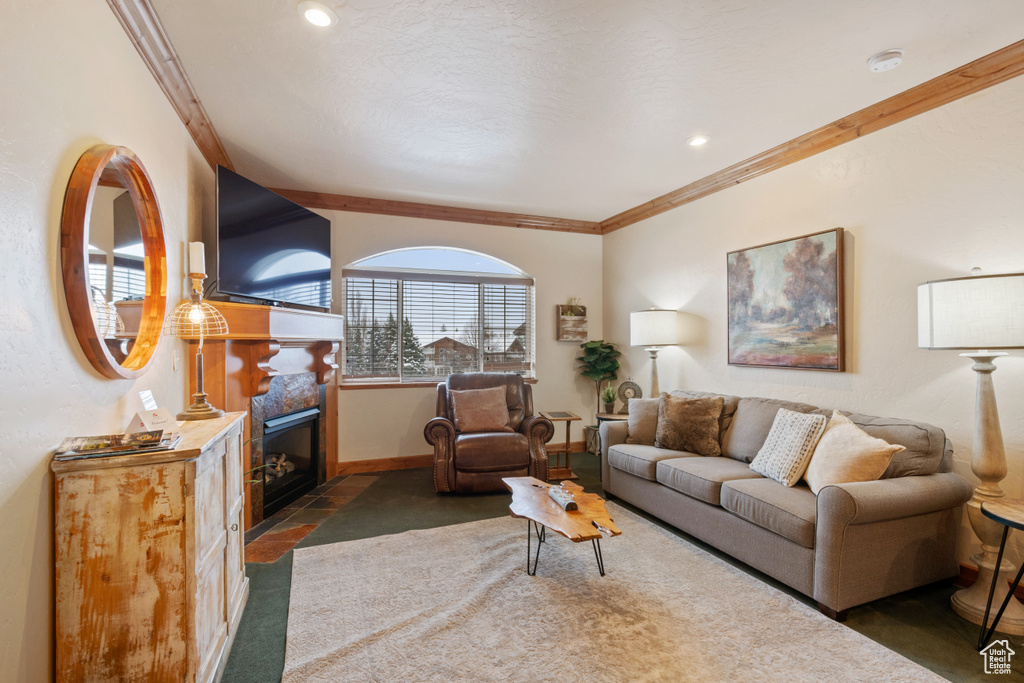 Living area featuring a fireplace with flush hearth, ornamental molding, carpet flooring, and baseboards