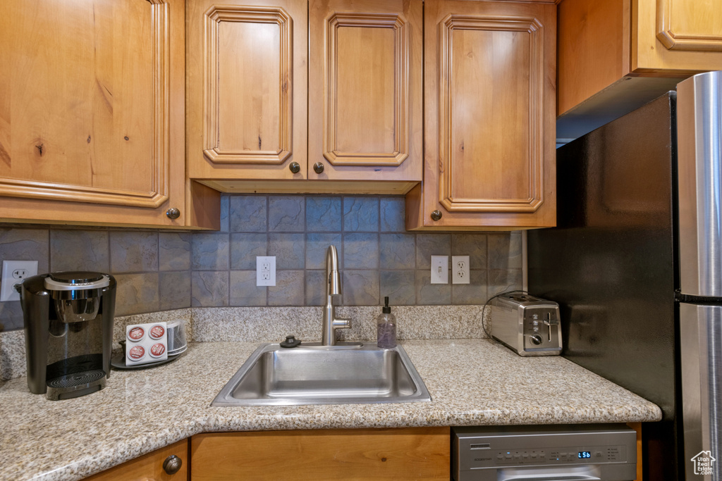Kitchen featuring stainless steel appliances, a sink, light countertops, and decorative backsplash