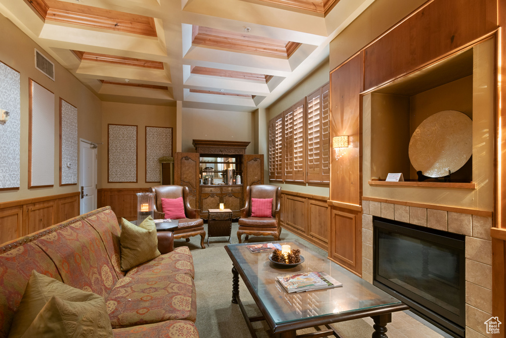 Living room with visible vents, coffered ceiling, a tile fireplace, wainscoting, and beam ceiling