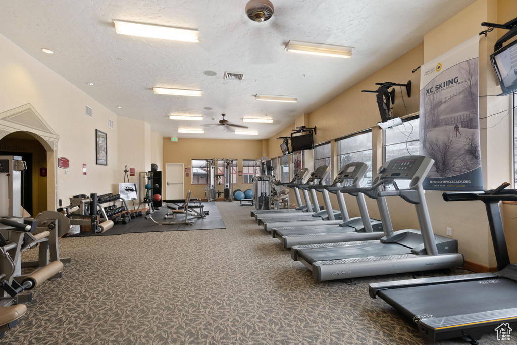 Exercise room featuring a textured ceiling, visible vents, and a ceiling fan
