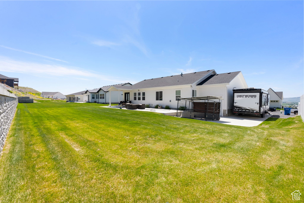 Back of house with a jacuzzi, a patio area, a lawn, and a residential view