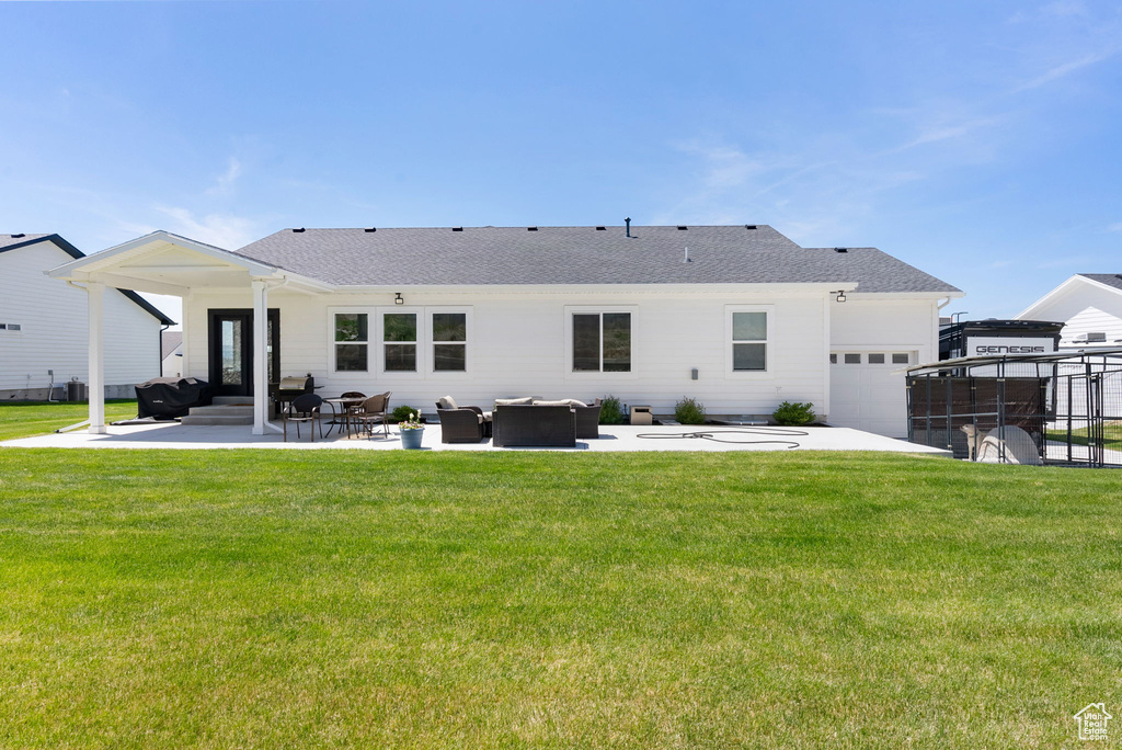 Back of house featuring a patio area, a shingled roof, a yard, and an attached garage