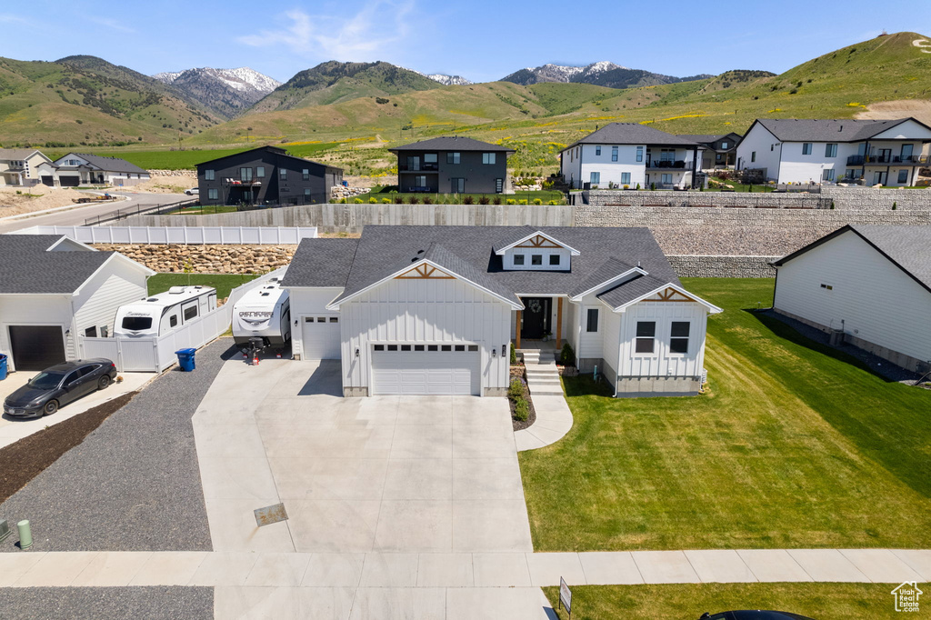View of front of home featuring board and batten siding, an attached garage, a residential view, a mountain view, and roof with shingles