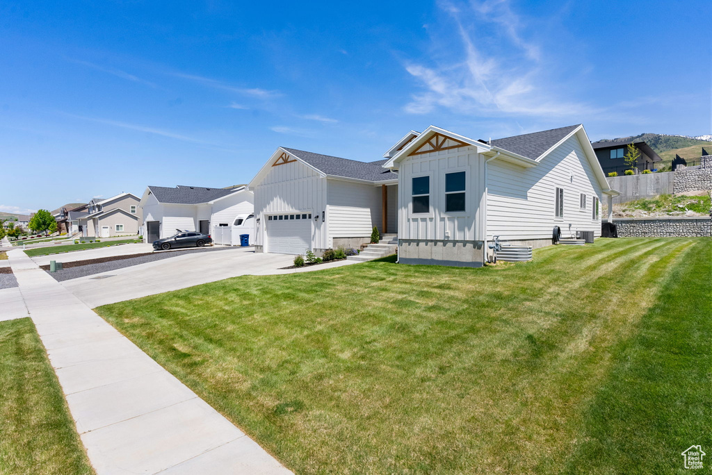 View of front of home with board and batten siding, concrete driveway, a front yard, a residential view, and a garage