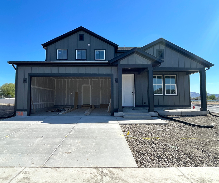 View of front of property with concrete driveway, an attached garage, and board and batten siding