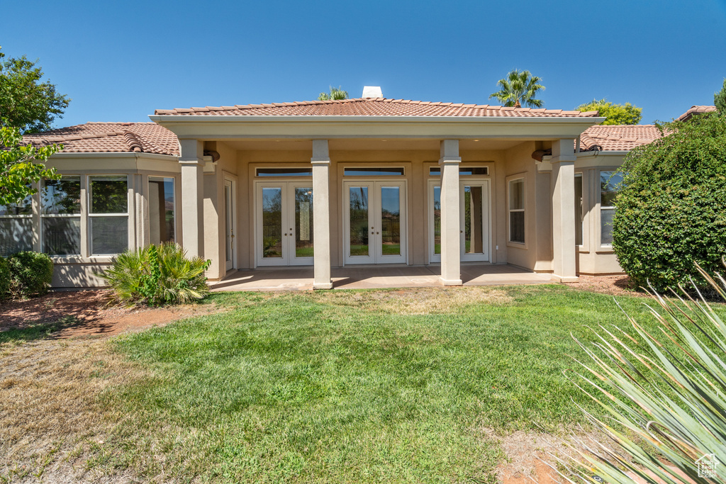 Rear view of house with french doors, a lawn, a tiled roof, and stucco siding