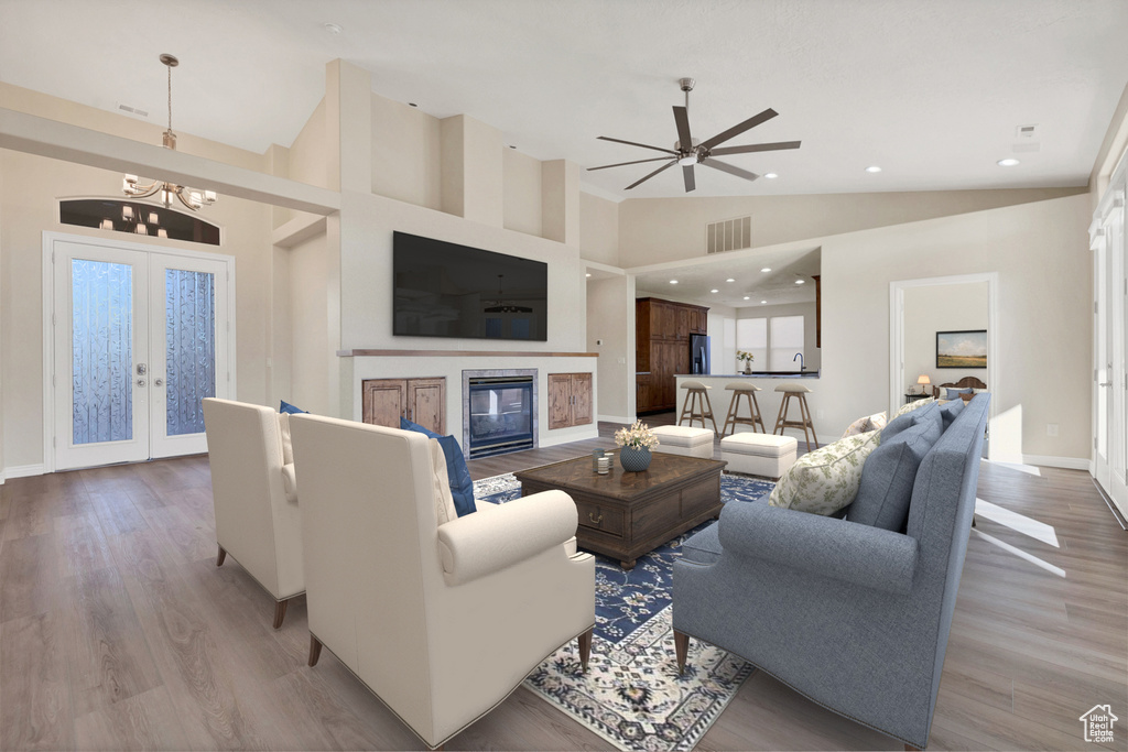 Living room featuring visible vents, a glass covered fireplace, french doors, light wood-style floors, and high vaulted ceiling