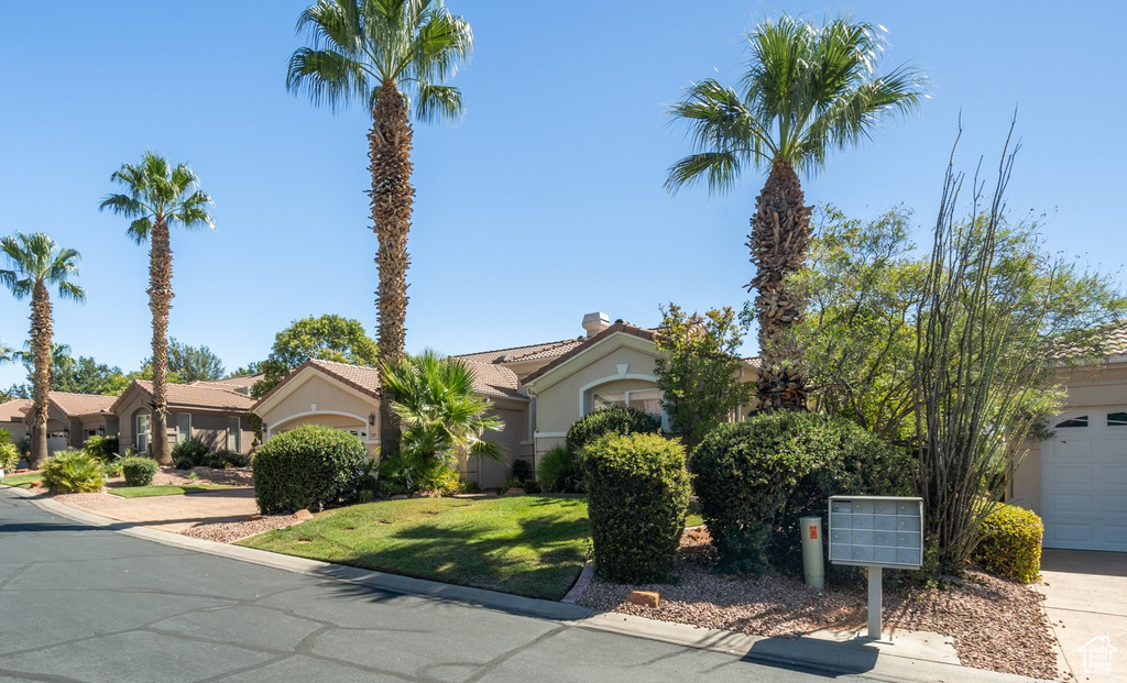 View of front of house with a tiled roof, a front lawn, a residential view, and stucco siding