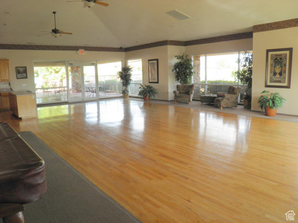 Living area featuring lofted ceiling, ceiling fan, visible vents, and wood finished floors
