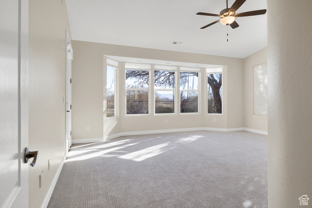 Empty room with lofted ceiling, carpet flooring, visible vents, and baseboards