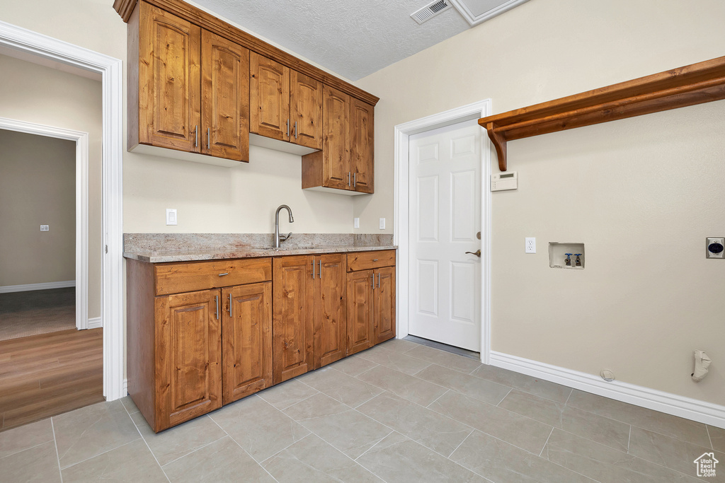 Kitchen with brown cabinets, visible vents, a sink, and light tile patterned flooring