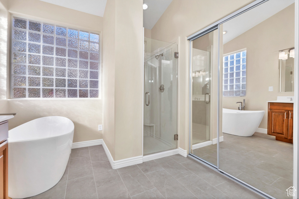 Full bathroom with a stall shower, baseboards, a freestanding bath, and vanity