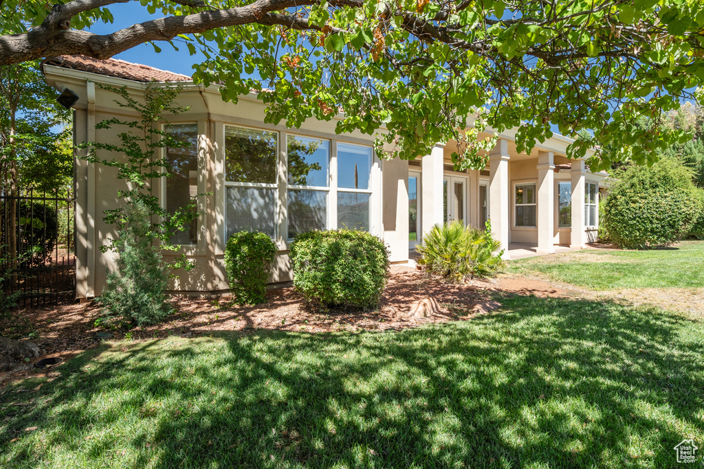 View of front of house featuring a front yard, a tile roof, and stucco siding