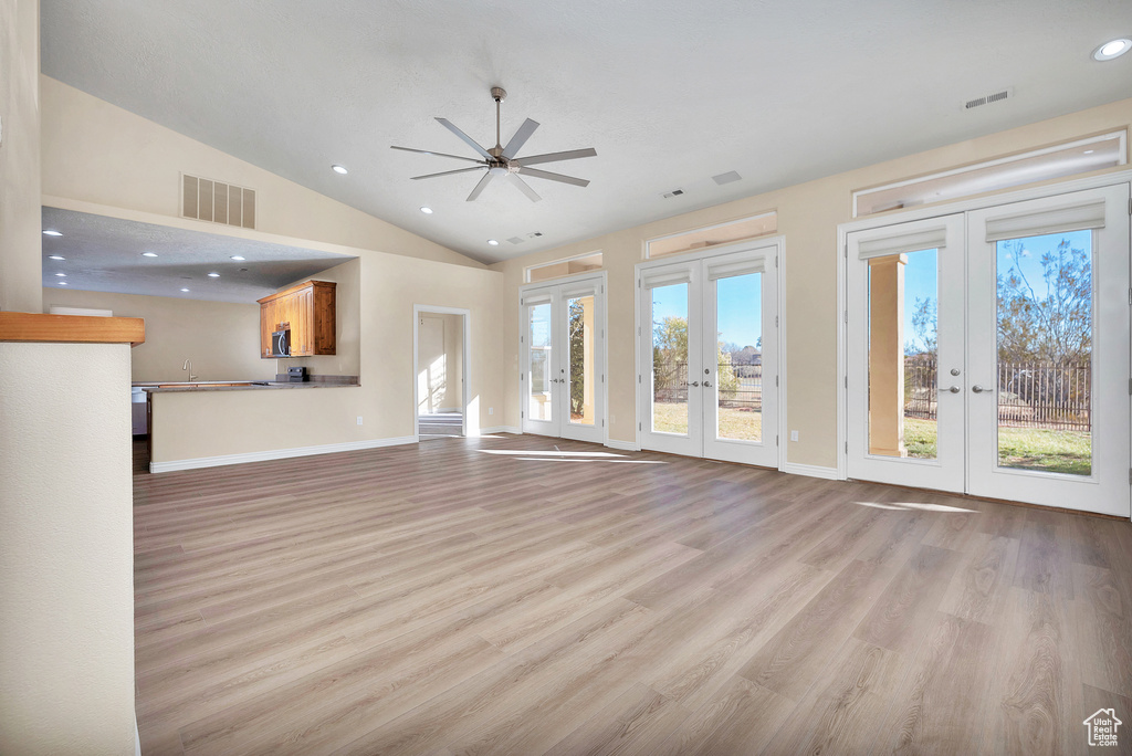 Unfurnished living room featuring light wood-style flooring, recessed lighting, visible vents, vaulted ceiling, and french doors